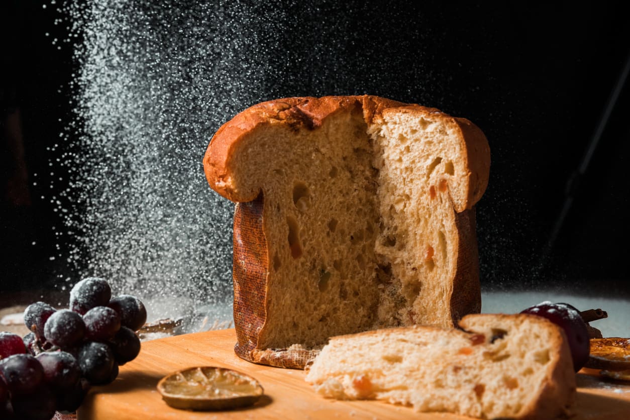 A loaf of bread with slices and flour dusting in the air.